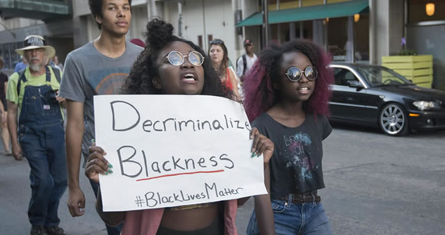 Protesters holding a sign that says Decriminalize Blackness